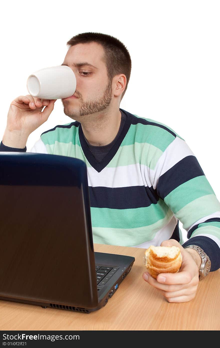 Man having his breakfast in front of his notebook. Man having his breakfast in front of his notebook