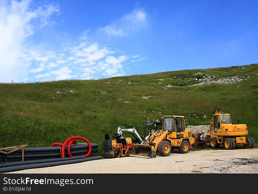 Two CAT working machines during a pause in a narrow broken street that crosses a valley. Location: Veneto, Italy. Two CAT working machines during a pause in a narrow broken street that crosses a valley. Location: Veneto, Italy.