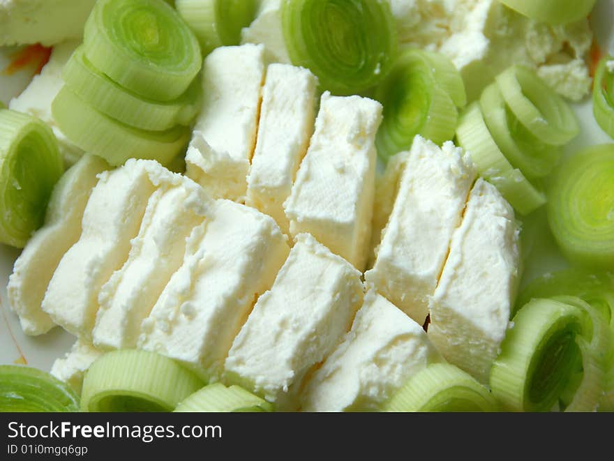 Cut green leek and white cheese slices closeup. Cut green leek and white cheese slices closeup