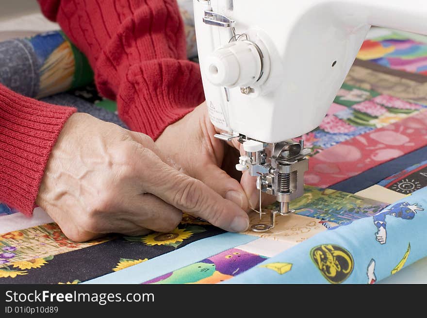 A female quilter is threading a needle on a sewing machine. A female quilter is threading a needle on a sewing machine.