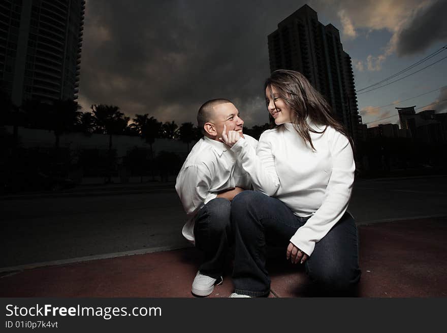 Happy young couple squatting in the street and showing affection towards eachother