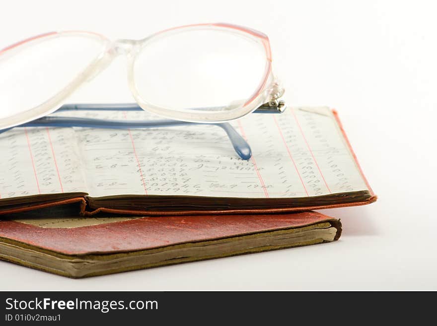 Two financial ledgers and a pair of glasses on a white background. Two financial ledgers and a pair of glasses on a white background