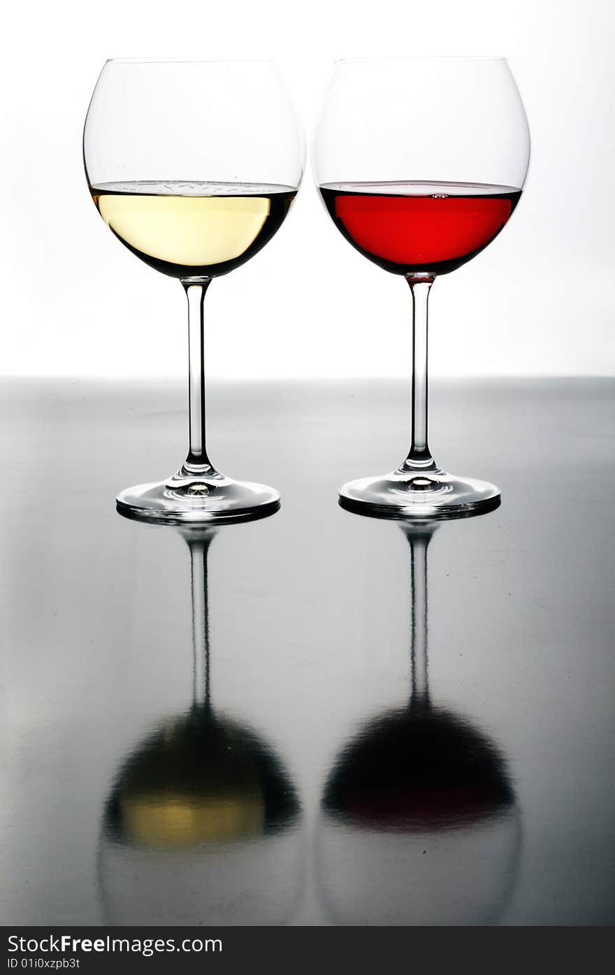 Two glasses of red and white wine on grey isolated on white with reflection