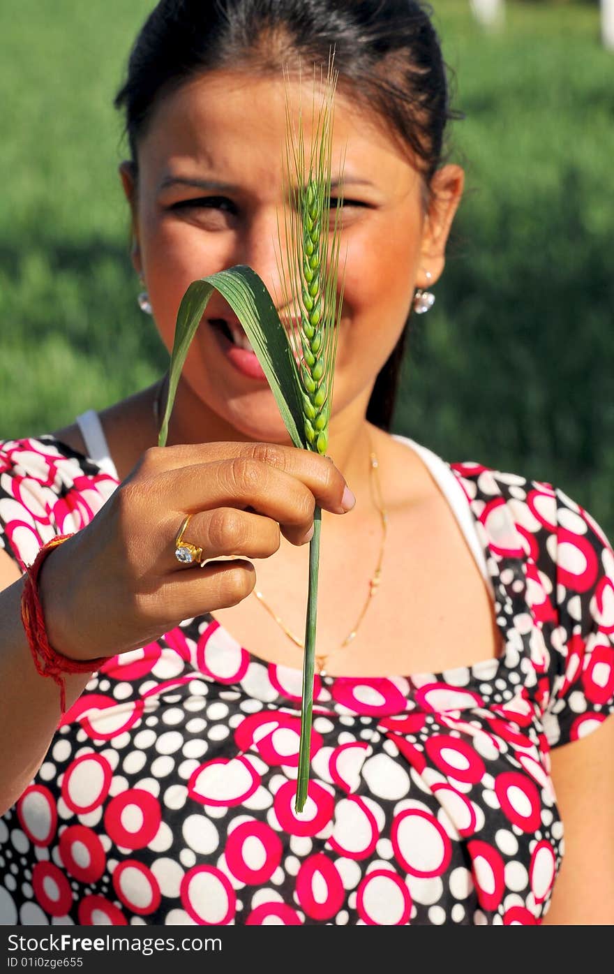 Girl holding a green wheat plant looking great.