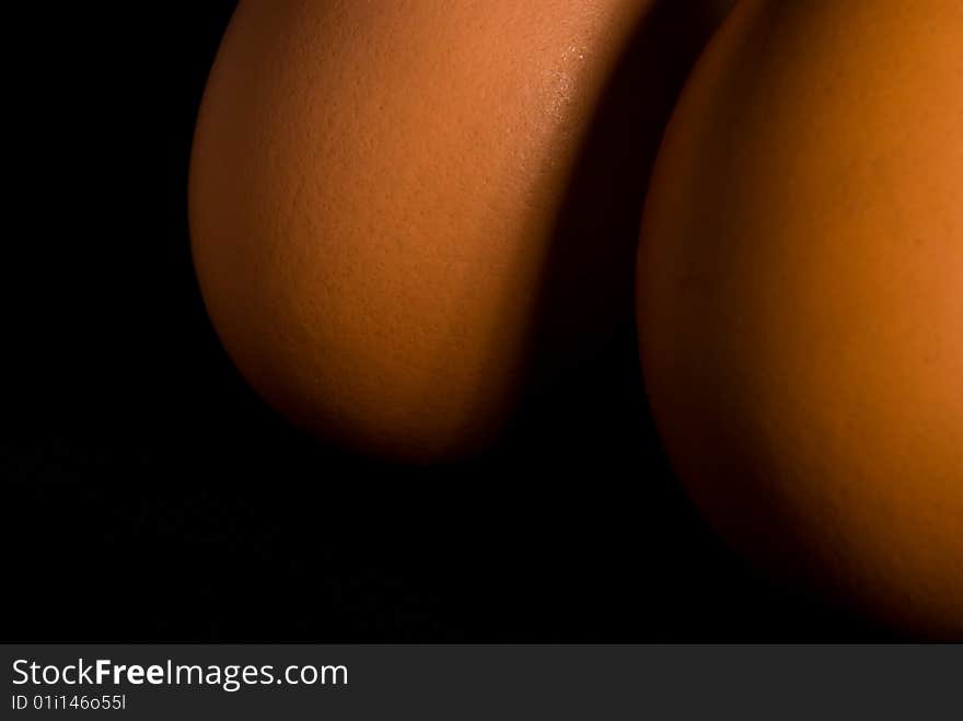 Two brown hen's eggs together in angled light with dark background. Two brown hen's eggs together in angled light with dark background