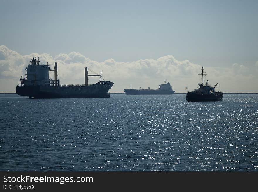 Silhouettes of three vessels anchored inside the breakwater. Silhouettes of three vessels anchored inside the breakwater.