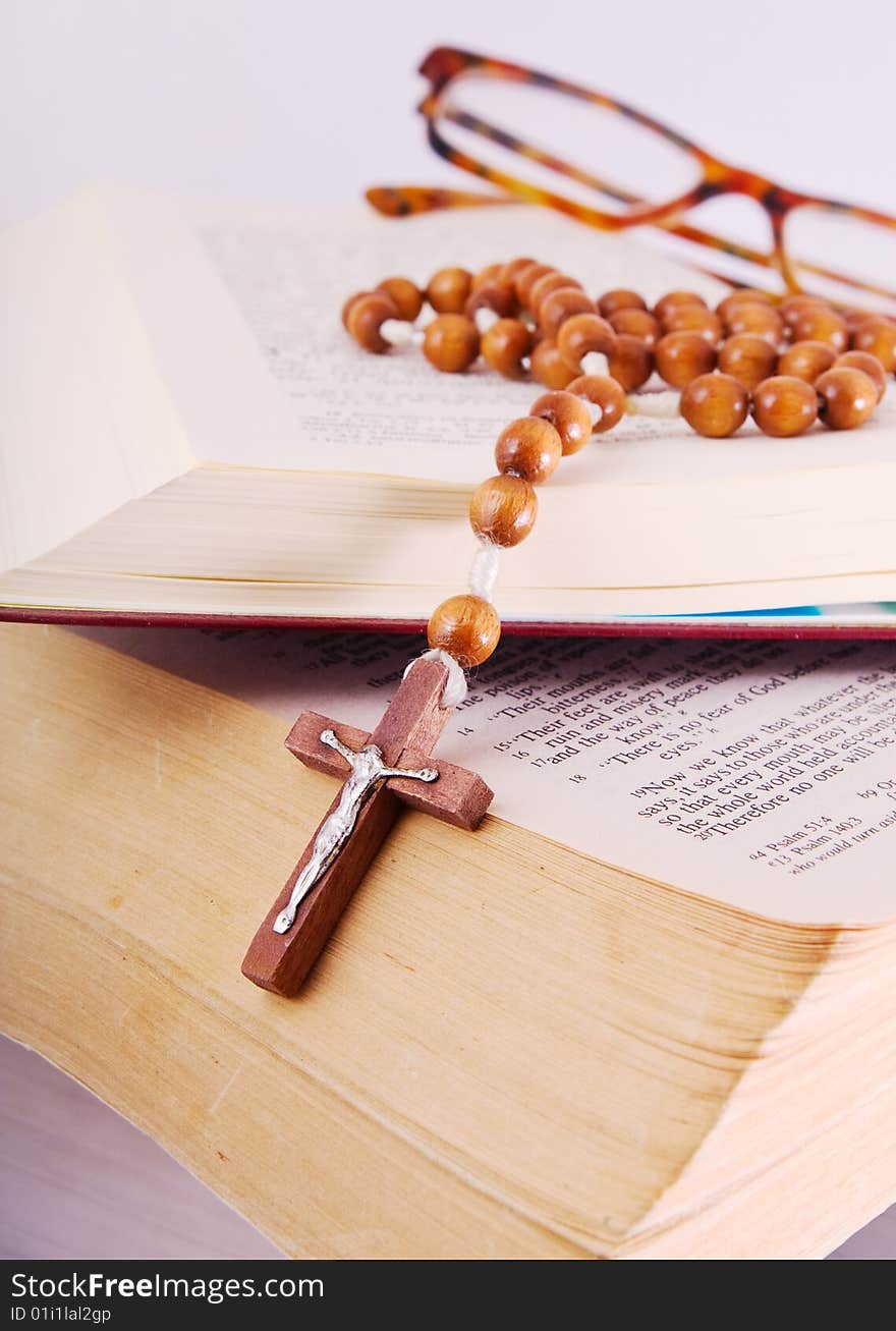 Open Holy Bible lying on stack of old books with glasses, cross and beads. Open Holy Bible lying on stack of old books with glasses, cross and beads