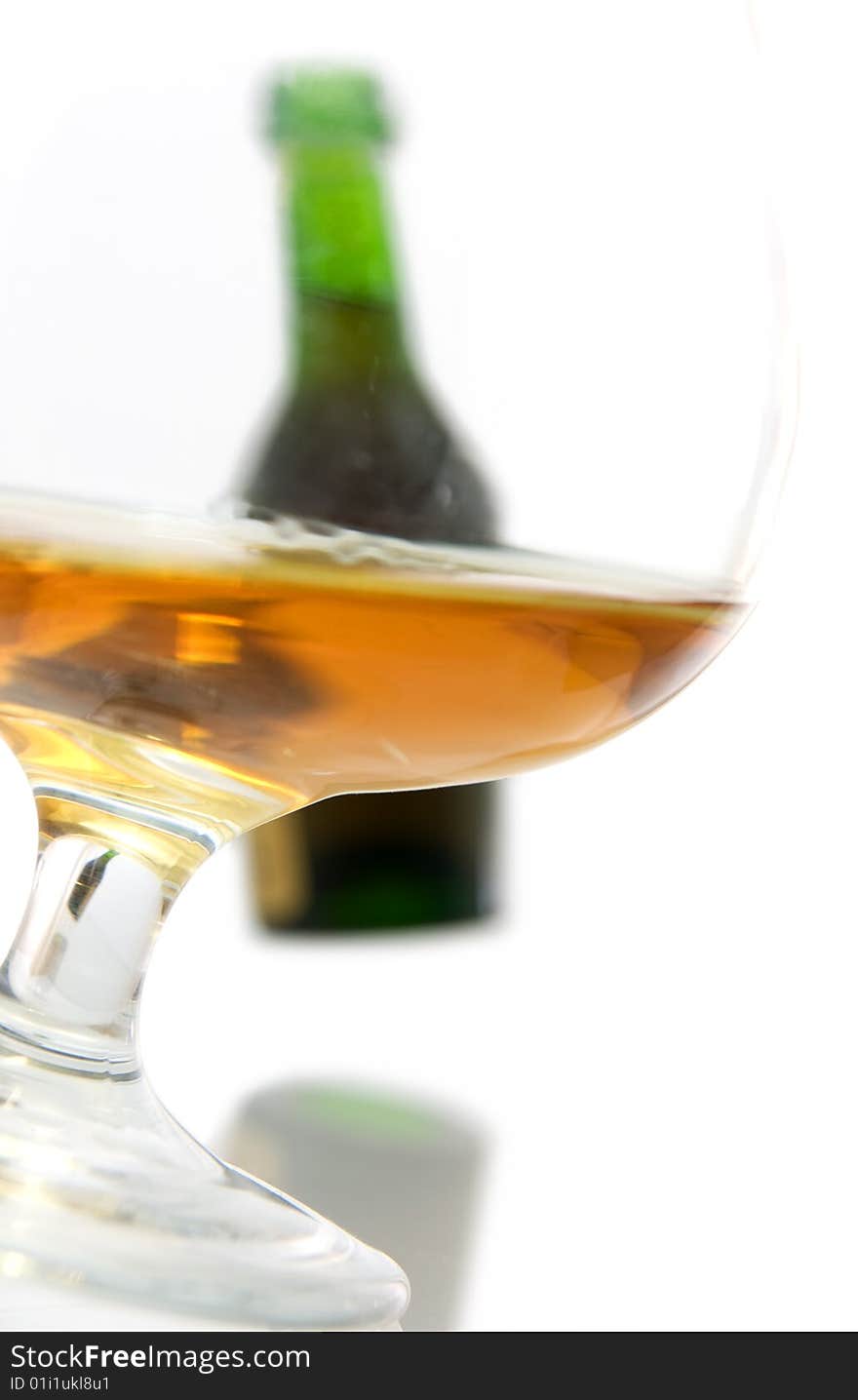 Isolated glass of brandy with a bottle in the background