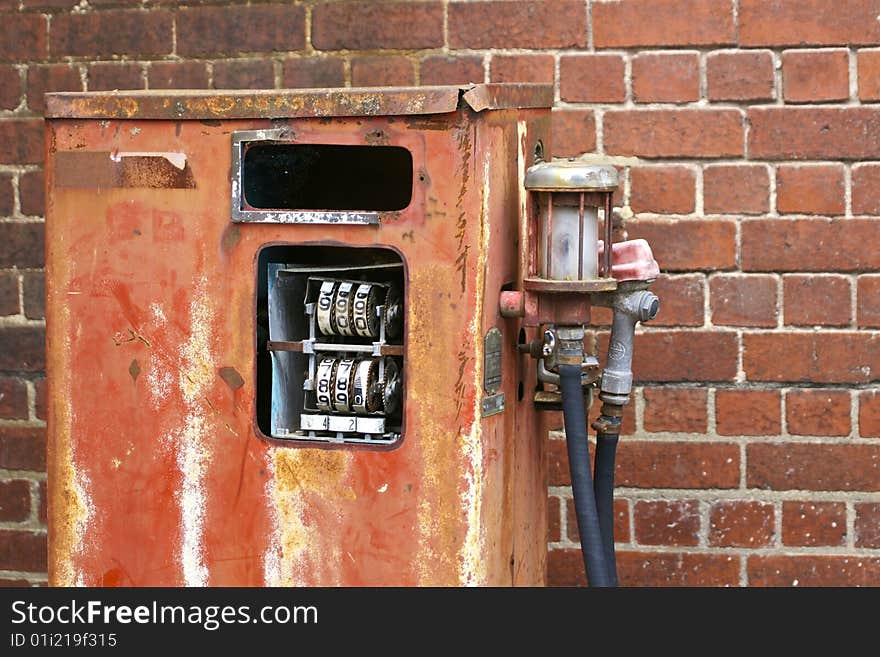 Dilapidated  petrol pump against a plain brick wall. Dilapidated  petrol pump against a plain brick wall