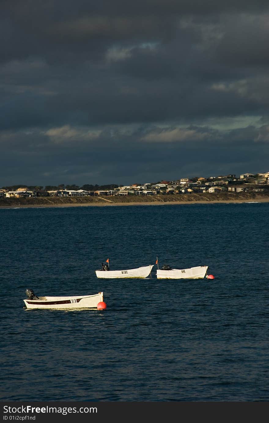 3 fishing boats at anchor off shore.