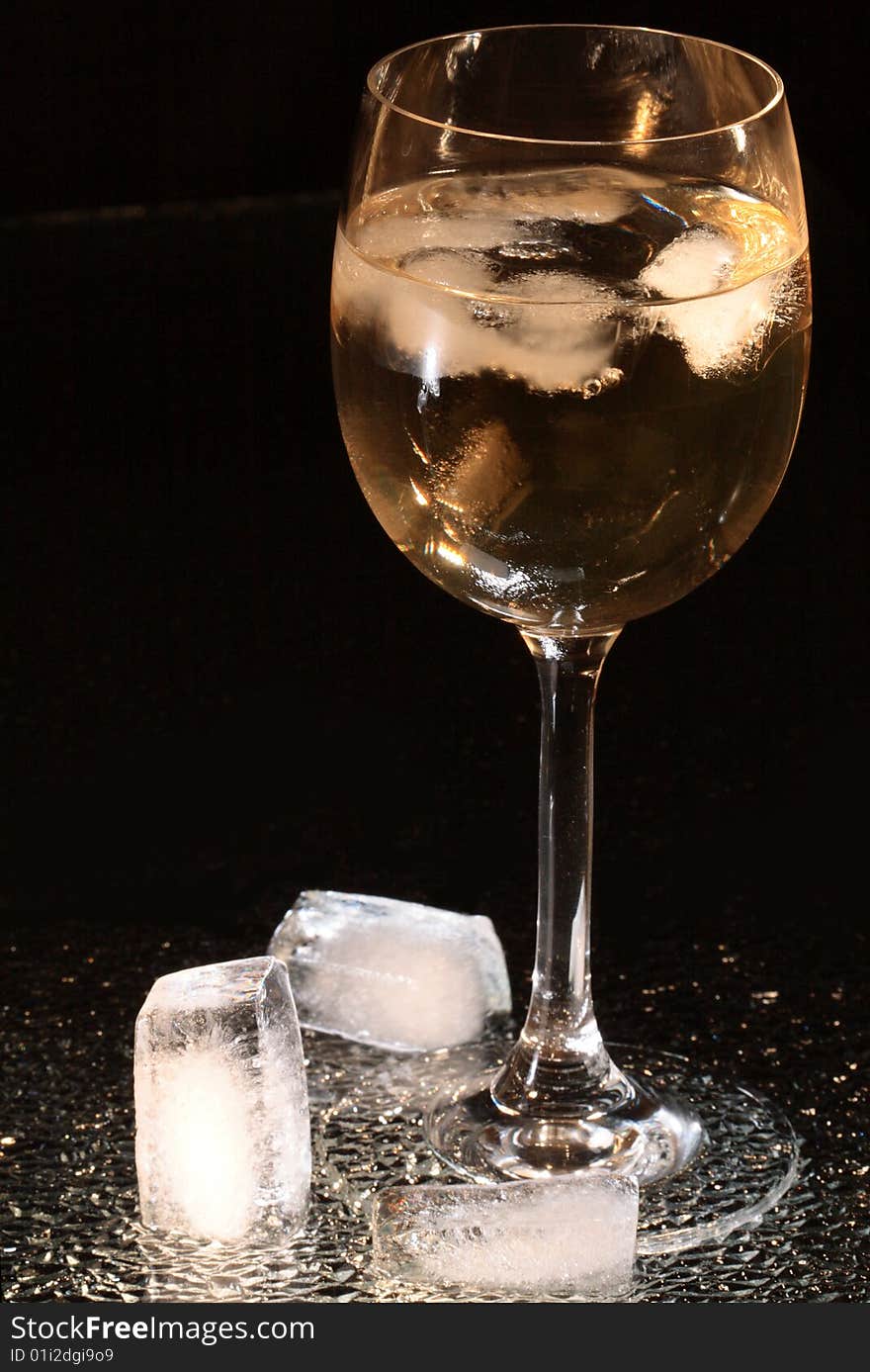 Ice cubes lying near wineglass on dark background. Ice cubes lying near wineglass on dark background