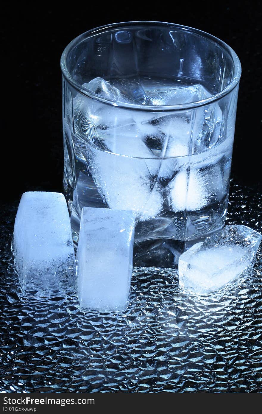 Ice cubes lying near wineglass on dark background. Ice cubes lying near wineglass on dark background