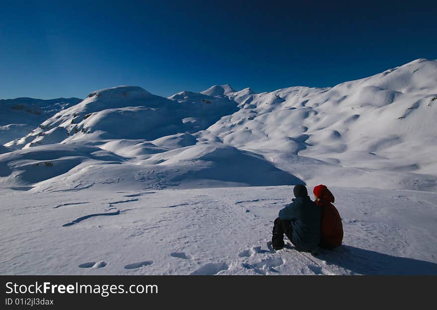 Couple admiring mountain view on the summit in alps in wiinter