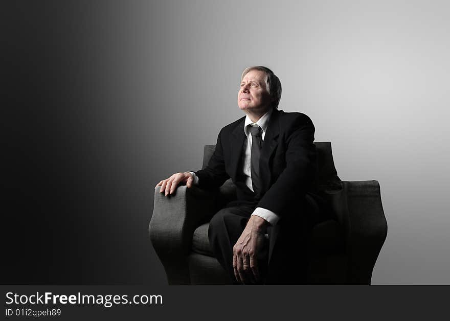 An hopeful senior man  sitting on an armchair