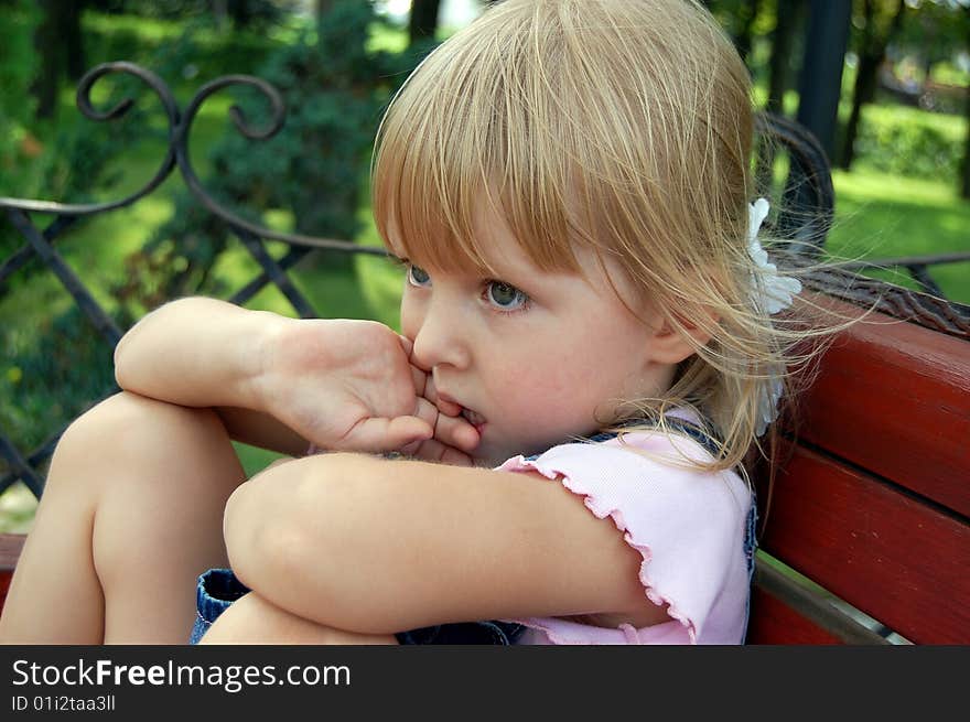 Thoughtful little girl  sit in park on bench. Thoughtful little girl  sit in park on bench