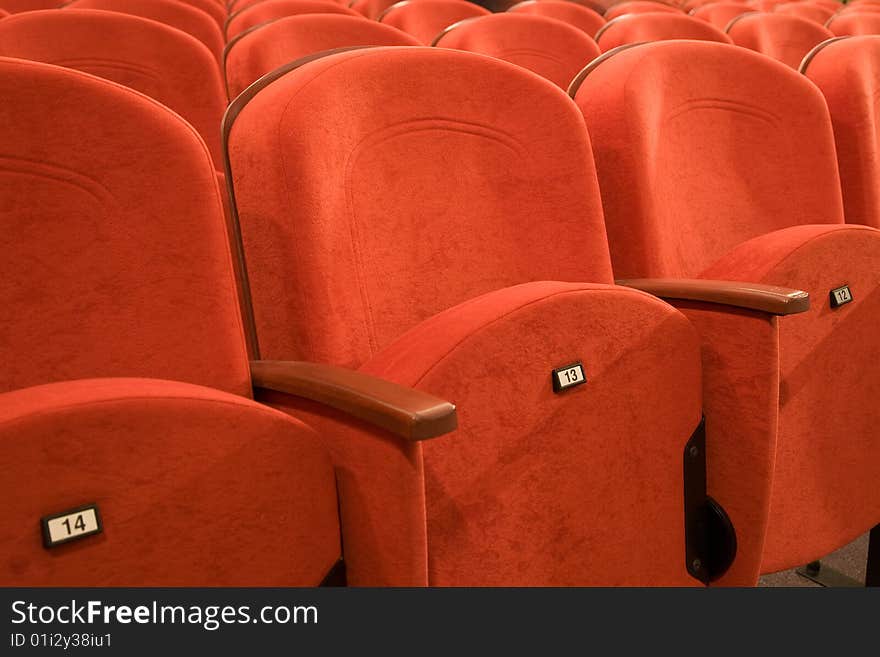 Seat number thirteen. Row of red chairs in auditorium. Seat number thirteen. Row of red chairs in auditorium.