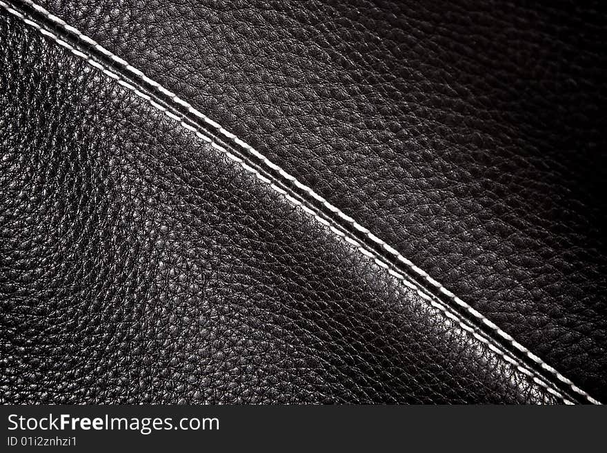 Black leather background stitched up by white thread