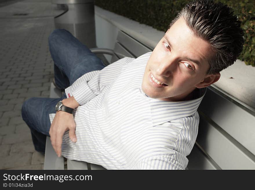 Handsome young man laying on a bench