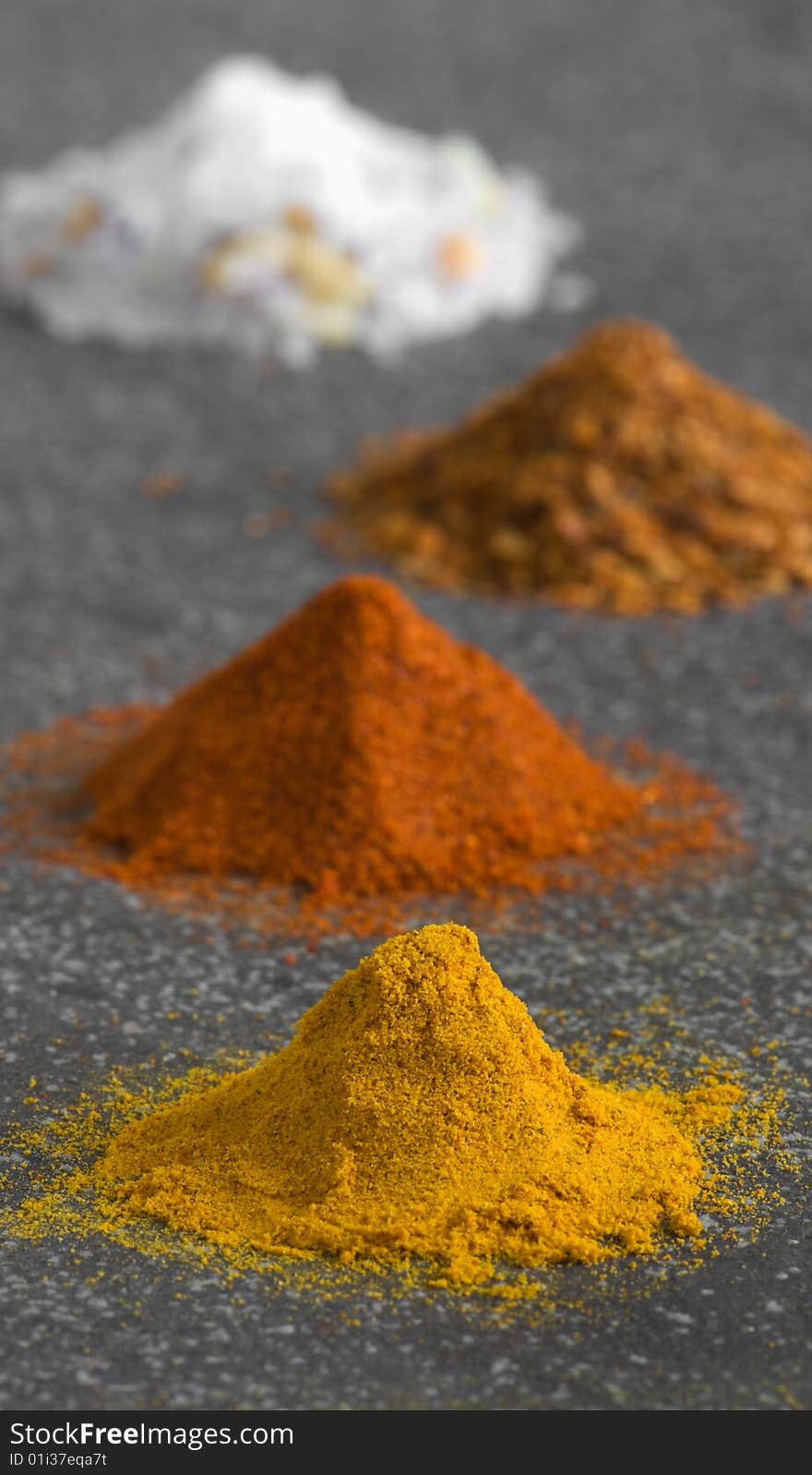 Four piles of ground spices on grey background