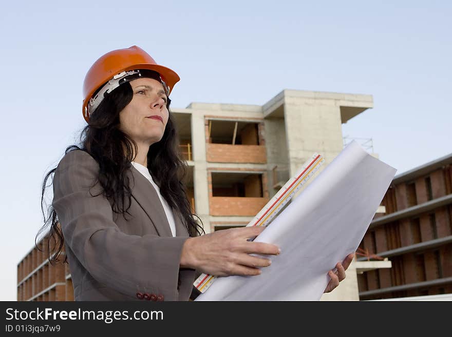 Female architect looking at blueprint in front of construction site