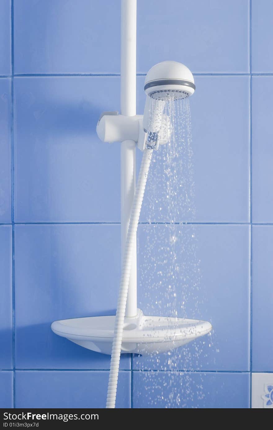 White shower and drops of water on blue tiling background