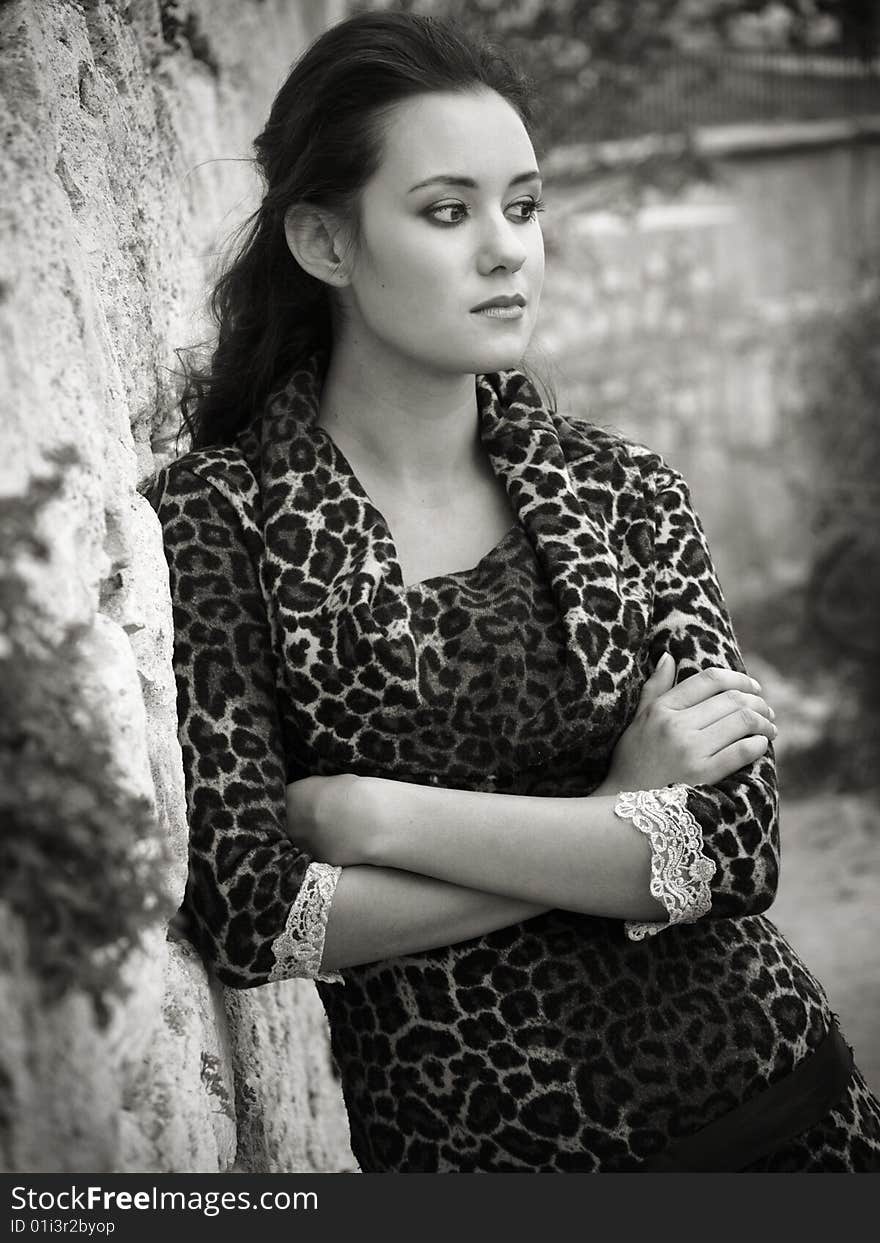 Beautiful girl standing near stone wall black-and-white shot. Beautiful girl standing near stone wall black-and-white shot