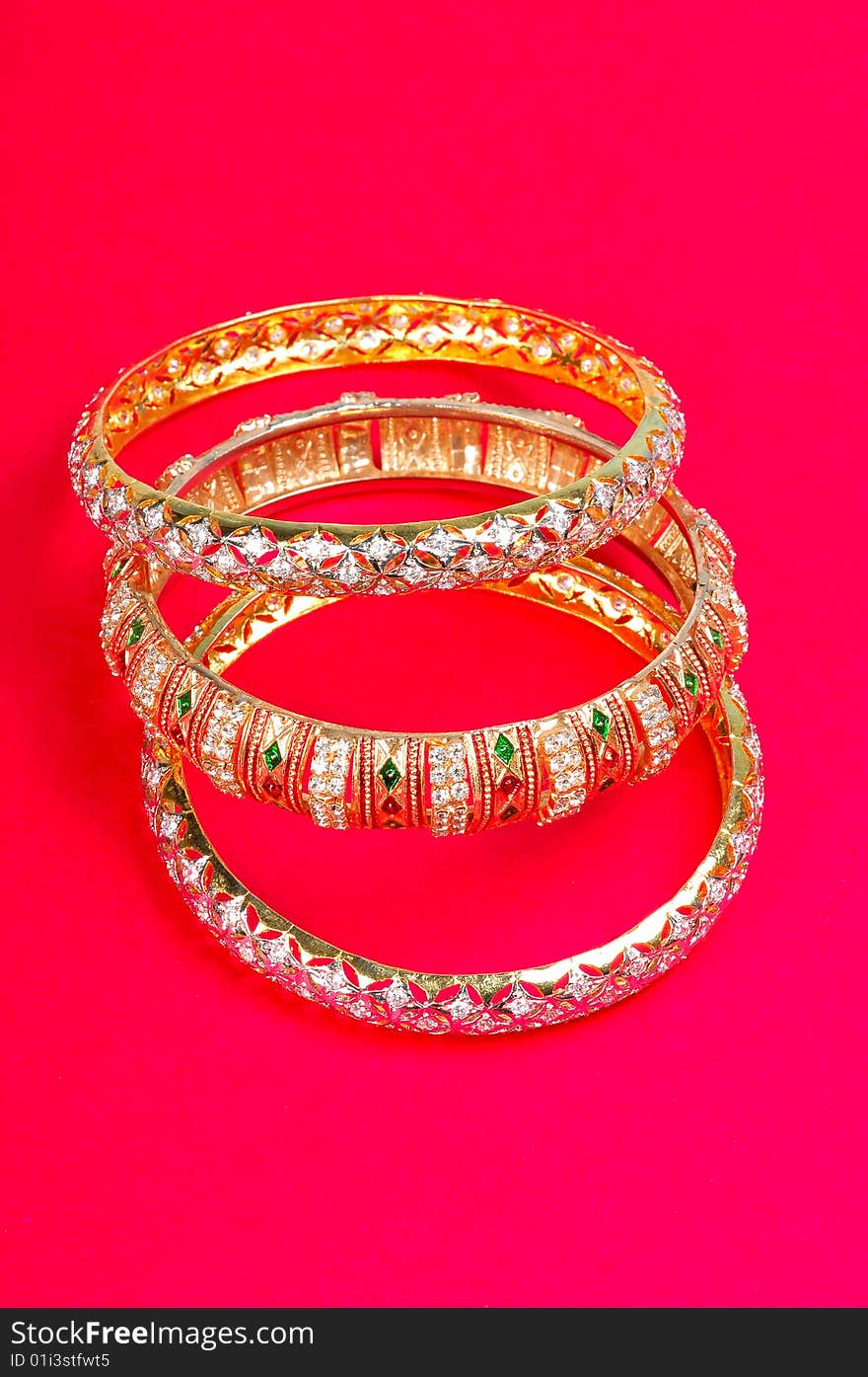 Golden bangles isolated on coloured background.