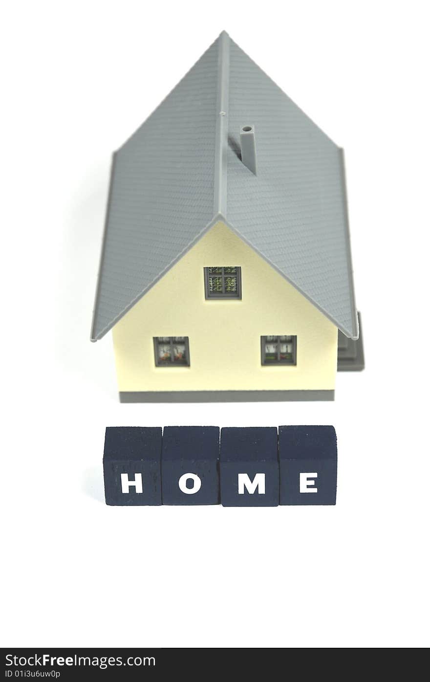 A miniature house with the word home in front of it. A miniature house with the word home in front of it