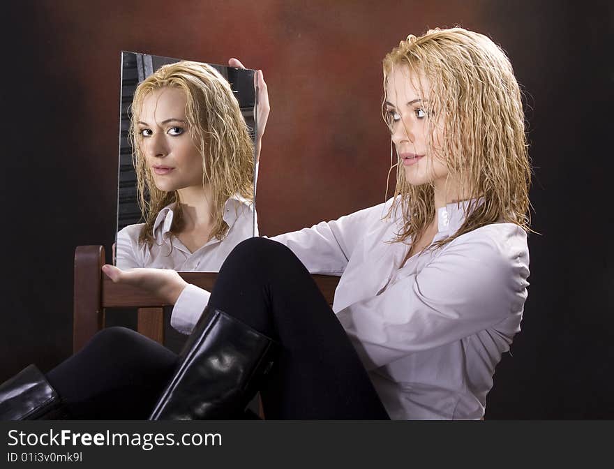 Curly wet haired blond sitting in chair looking at camera through mirror. Curly wet haired blond sitting in chair looking at camera through mirror