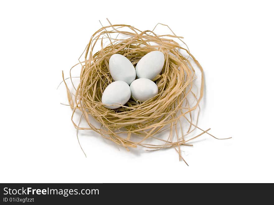 Straw nest with four white coated chocolate eggs, on white background. Straw nest with four white coated chocolate eggs, on white background.