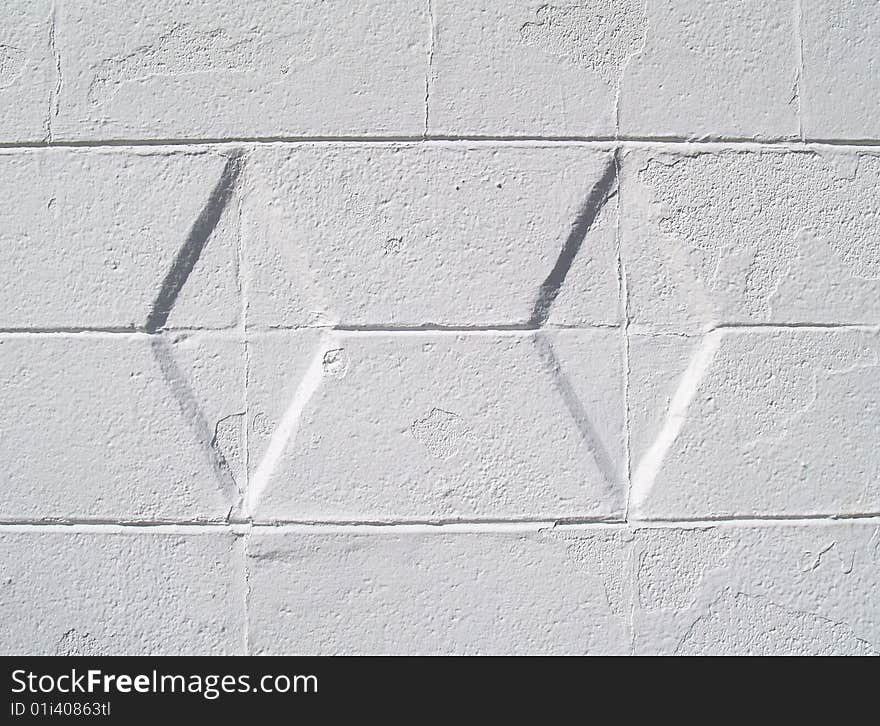 Close-up view of a white painted brick or block exterior wall with diamond texture. Close-up view of a white painted brick or block exterior wall with diamond texture.