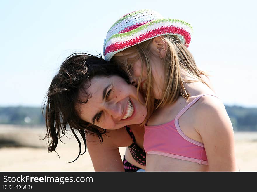 Mother and girl hugging at the beach