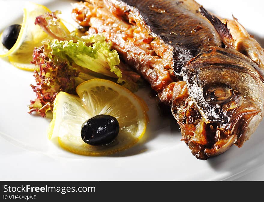 Fish Baked in Spicy Served with Salad Leaves, Lemon and Olives. Fish Baked in Spicy Served with Salad Leaves, Lemon and Olives