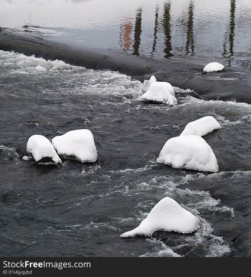 Stones in river with snow cover