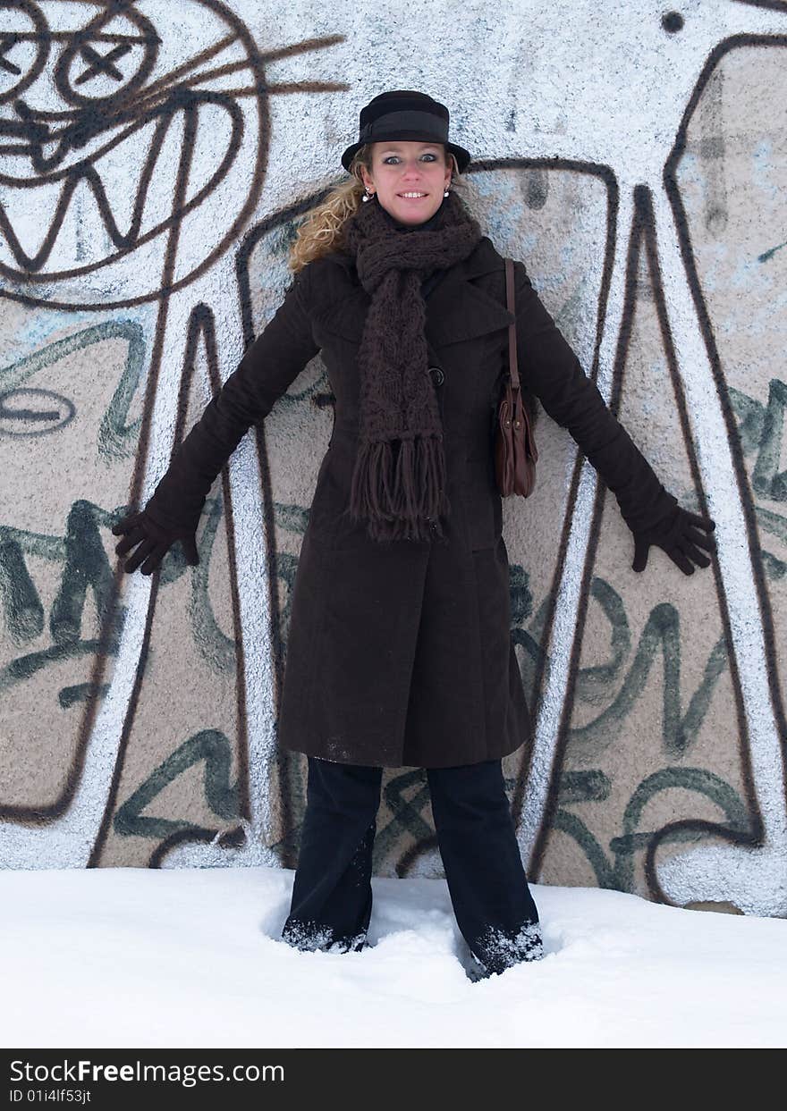 Girl with brown hat standing by concrete wall with graffiti