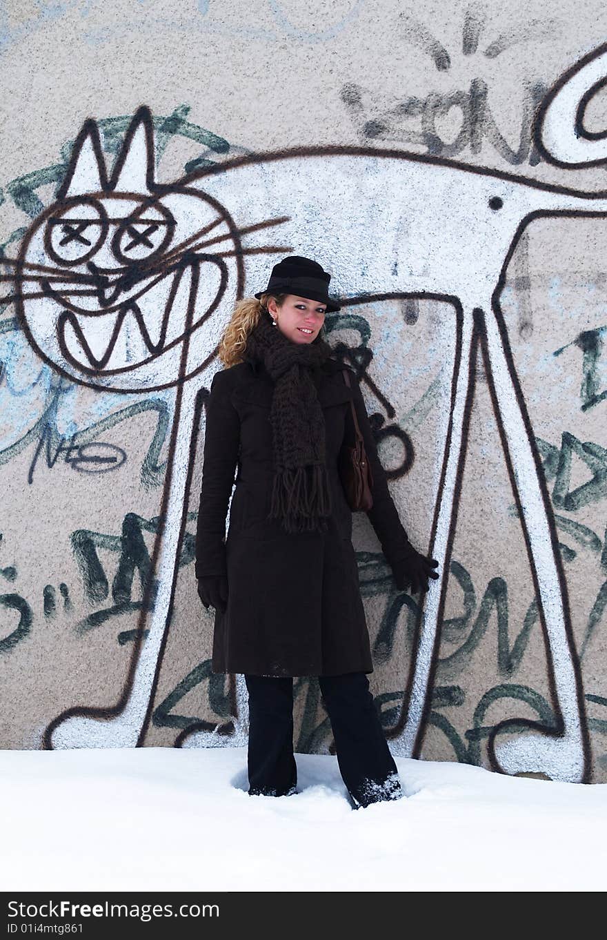 Girl with brown hat standing by concrete wall with graffiti