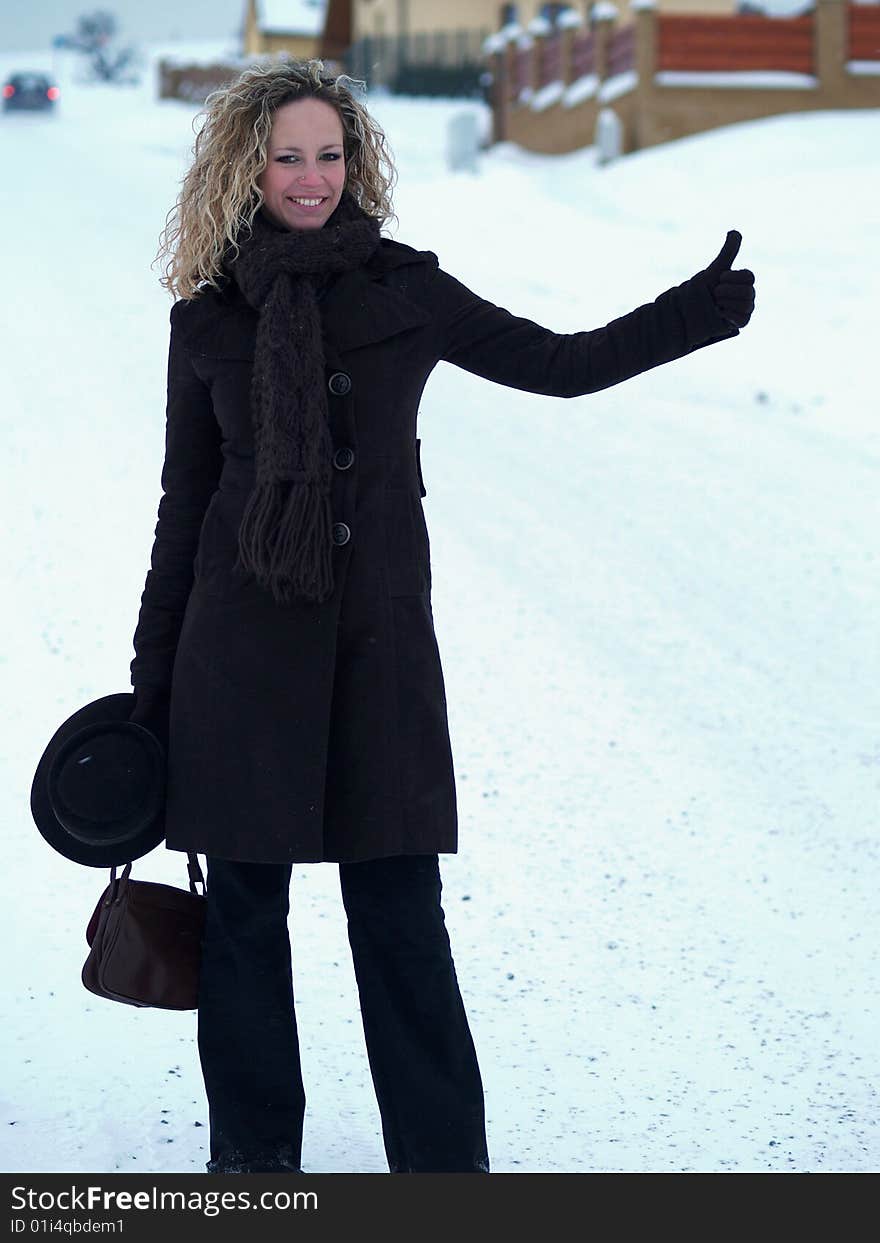 Curly girl hitchhiking in winter time