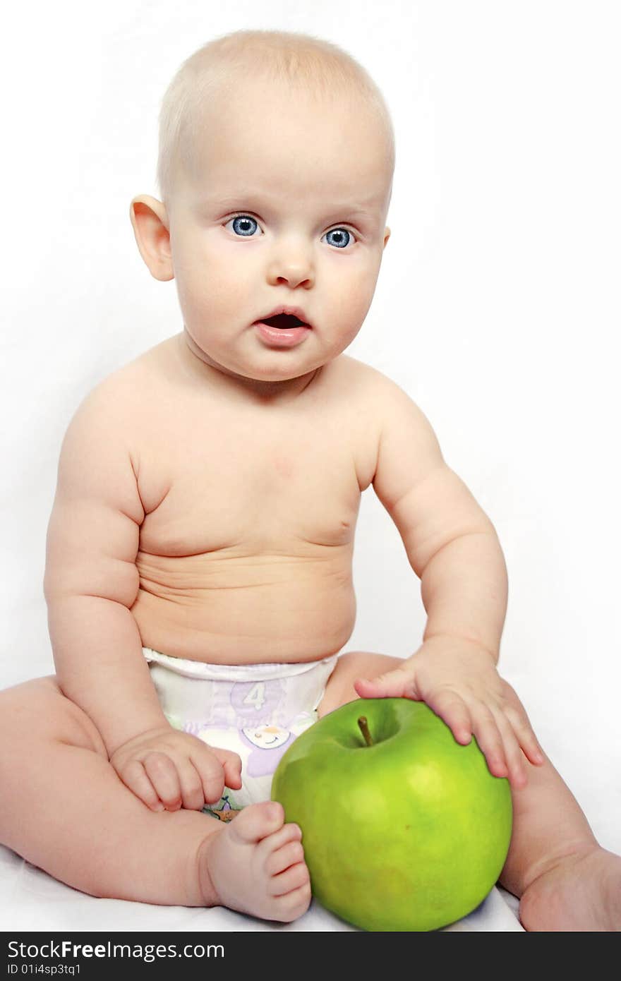 Beatiful baby boy is sitting and holding a very big apple. Background is white. Beatiful baby boy is sitting and holding a very big apple. Background is white.