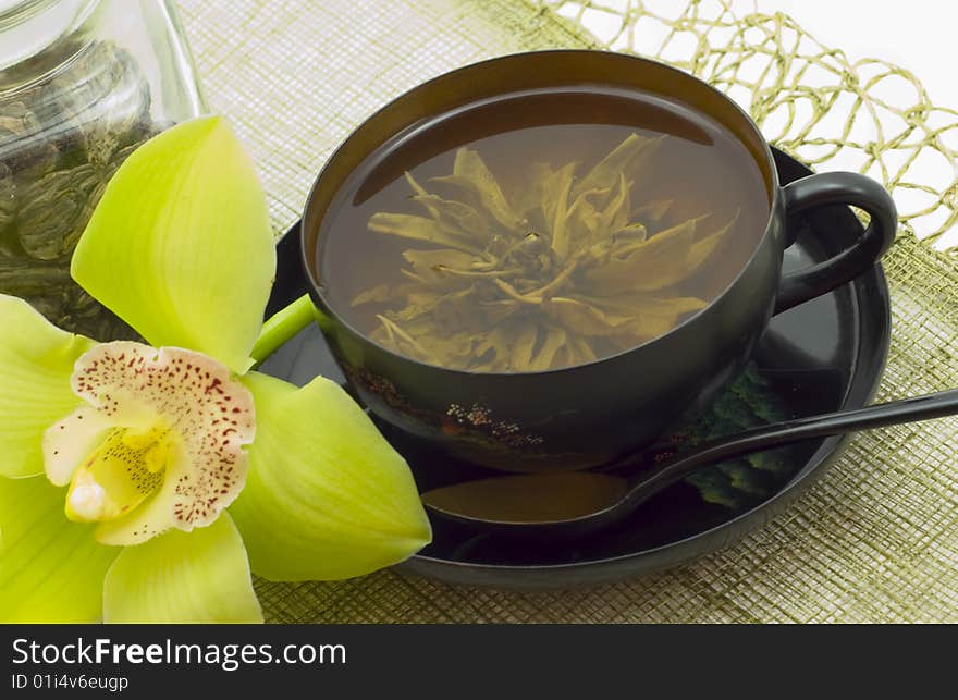 Green tea in beautiful black cup, devices and flower