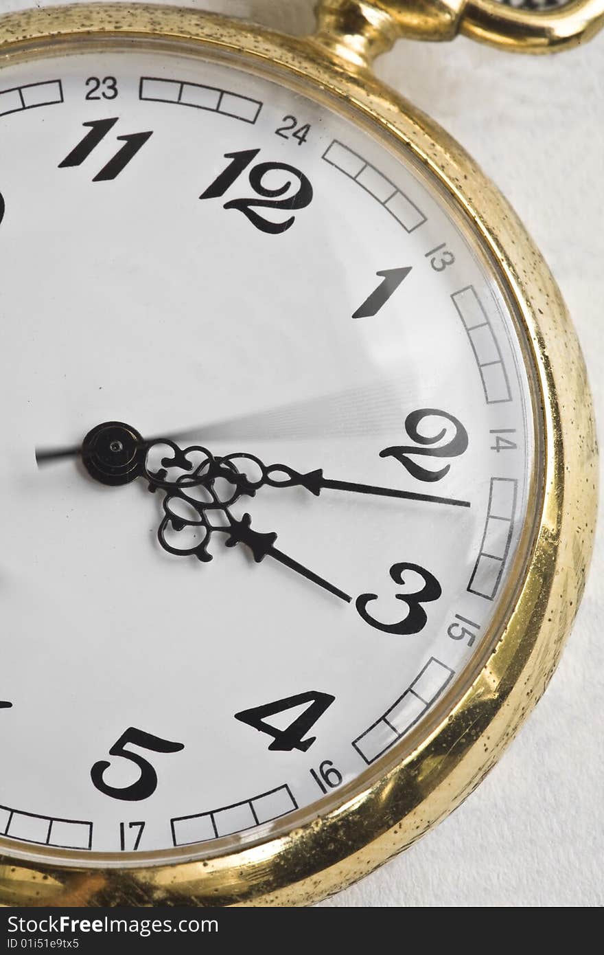 An antique pocket watch with classic numbers and golden casing, on a book. An antique pocket watch with classic numbers and golden casing, on a book.