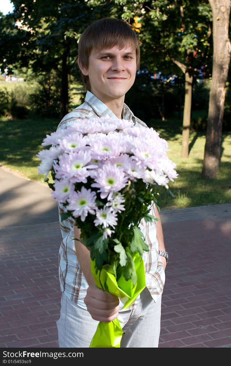 A boy is on a date in a park. He is holding a bouquet of flowers in his hand. A boy is on a date in a park. He is holding a bouquet of flowers in his hand.