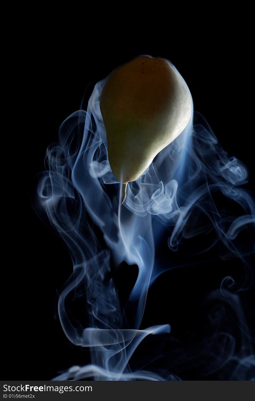 Green pear enveloped by smoke on a black background. Green pear enveloped by smoke on a black background