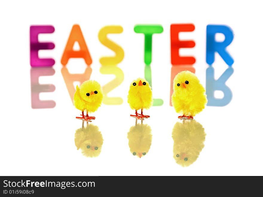 Baby chicks reflected in white with colorful easter word in background