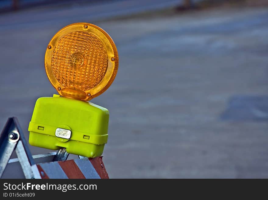 A orange and yellow construction light mounted on a barricade. A orange and yellow construction light mounted on a barricade