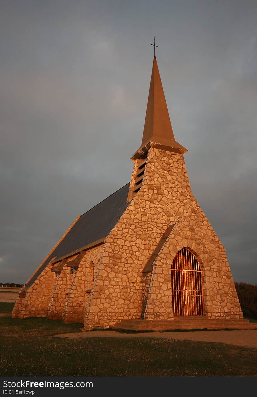 An old stone church at sunset, located on top of a cliff at Etretat, France. An old stone church at sunset, located on top of a cliff at Etretat, France.