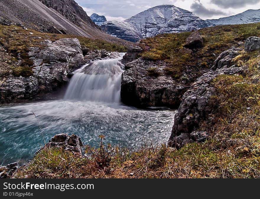 A small waterfall cascades into a small pool in the northern rocky Mountains west of Fort Nelson, BC Canada. A small waterfall cascades into a small pool in the northern rocky Mountains west of Fort Nelson, BC Canada