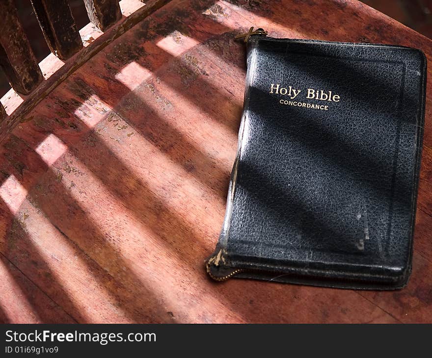 Black Leather Bible On Old Wooden Sunlit Chair