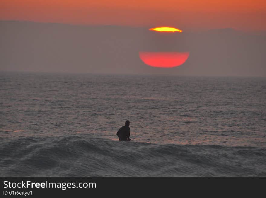 Surfer waiting for waves at dawn