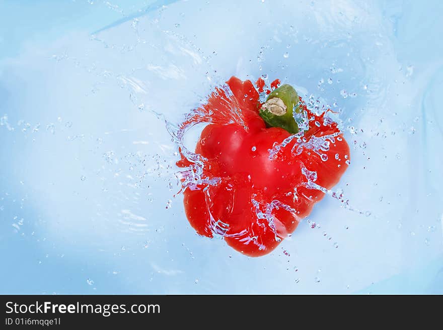 Red pepper falling into blue water