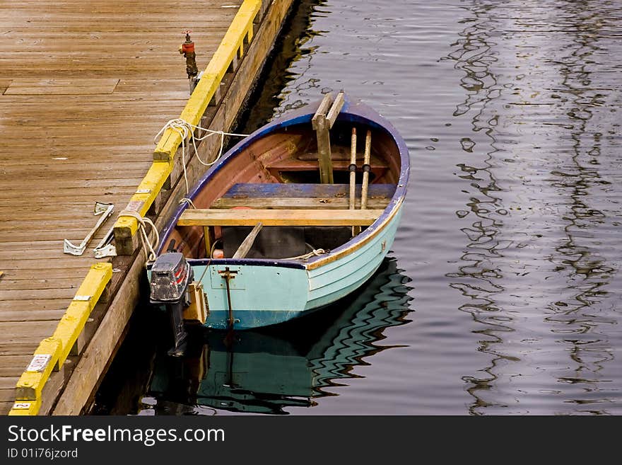 Blue Fishing Boat Tied To Yellow Pier